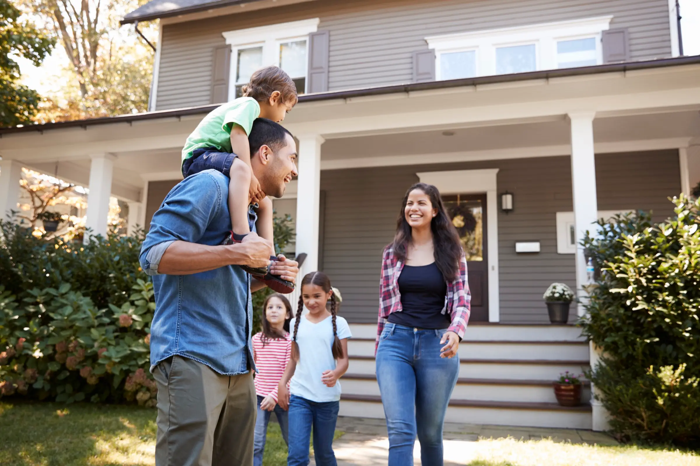 A family walking up to their home on a sunny day